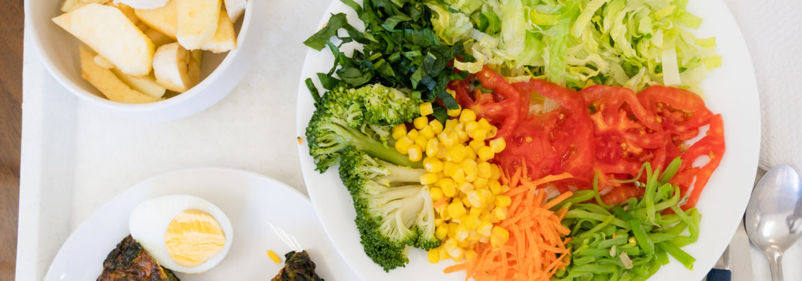 Vegetable salad, spinach omelette and fruit menu plates on tray