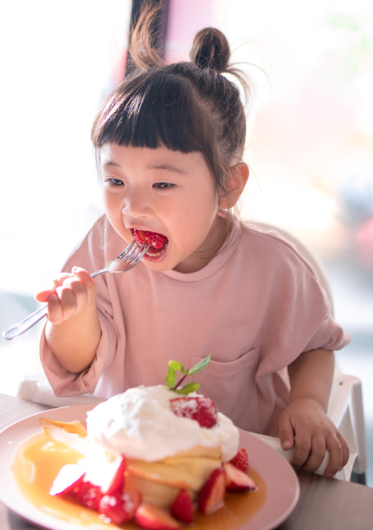 Little girl eating hot cake in cafe