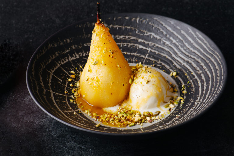 Boiled pear and icecream sprinkled with nuts in exquisite dessert.