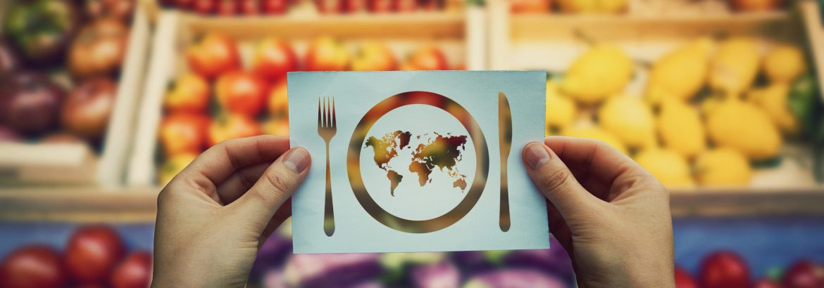 Global hunger issue, water supply problem. Hands holding a paper sheet with world map in a plate with knife and fork icon over market shelves background. International craving and starvation metaphor.