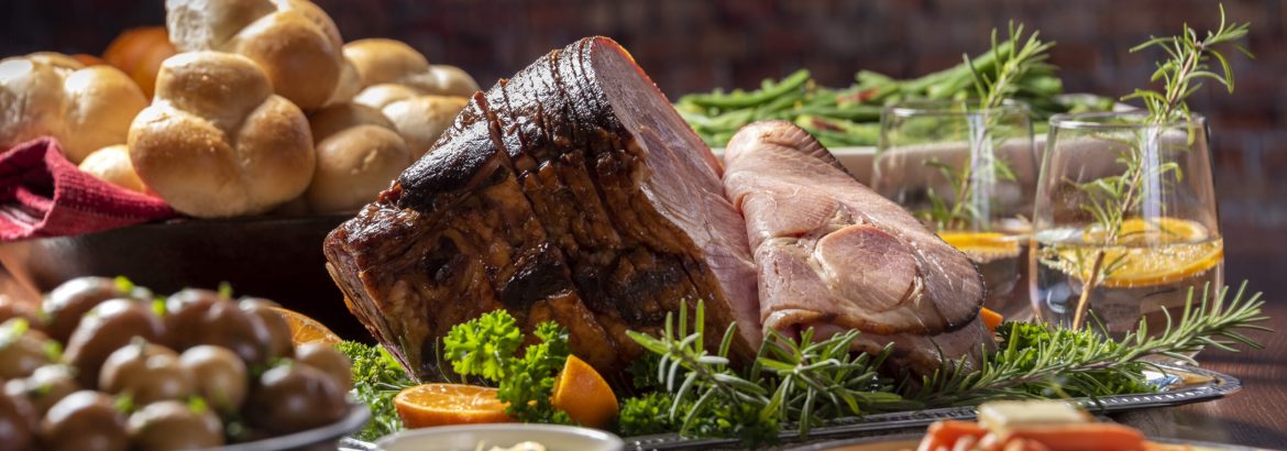 Holiday baked spiral cut ham with all the side dishes, carrots, green beans, potatoes and dinner rolls.