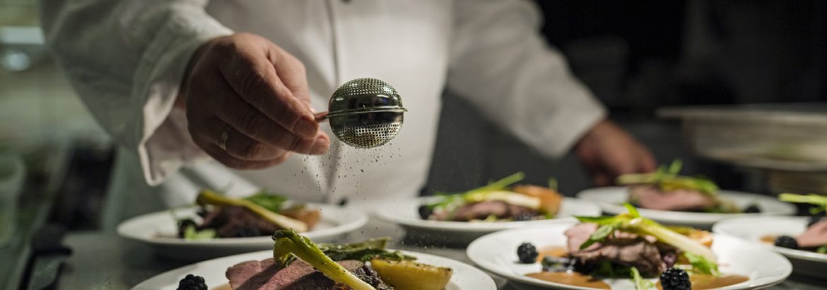 Chef preparing a dish of venison with apple and seasonal vegetables.