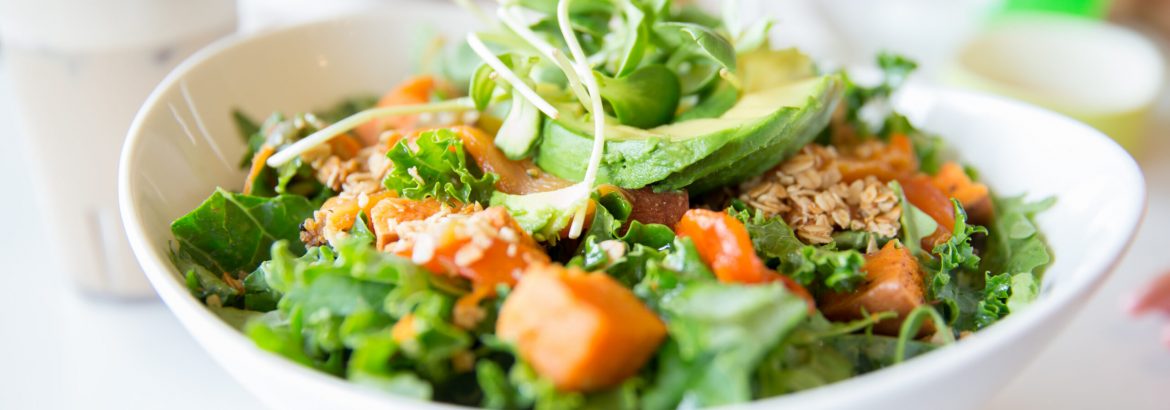 Healthy salad made up of avocado, kale, arugula, carrots and sweet potato