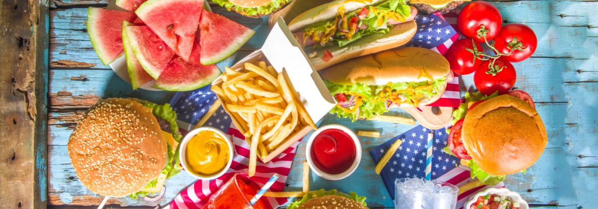 Fourth of July, Memorial Day, USA Independence Day concept. Patriotic, American traditional food. Picnic party with watermelon, burgers, hot dogs, drinks, blue wooden outdoor table background