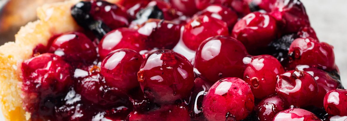 Tart, pie, cake with jellied fresh cranberries, bilberries and winter spices on a grey stone background. Copy space