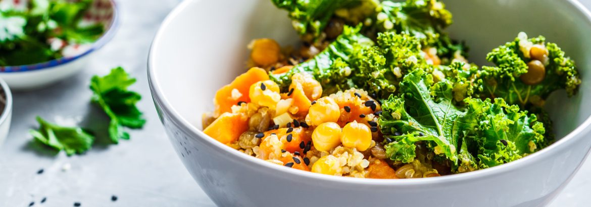 Vegan stew with chickpeas, sweet potato and kale in a white bowl.