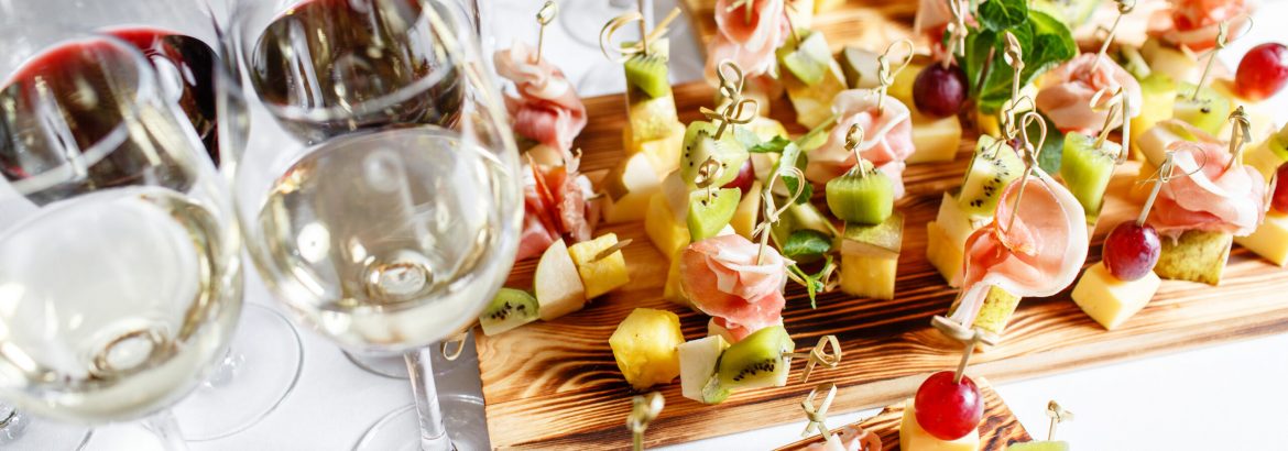 solemn happy new year banquet. Lot of glasses champagne or wine on the table in restaurant. buffet table with lots of delicious snacks. canapes, bruschetta, and little desserts on wooden plate board.