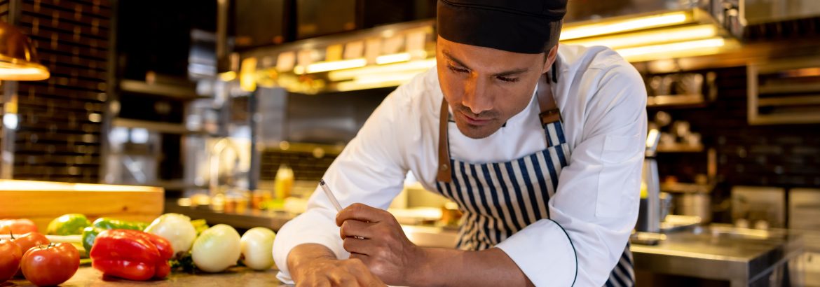 Latin American cook working at a restaurant and looking at a recipe online using a tablet computer - food service concepts