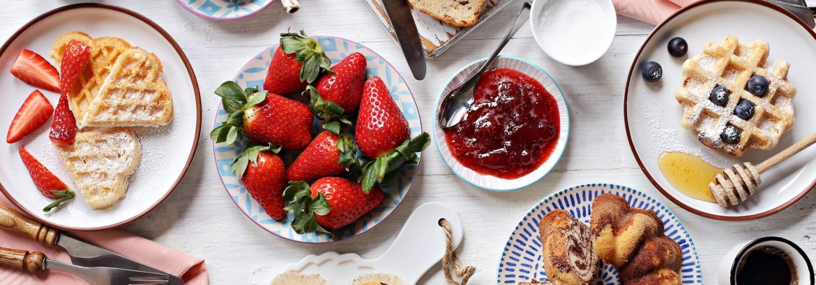 Festive family dessert table with cakes, waffles, sweets and fresh strawberry. Overhead view