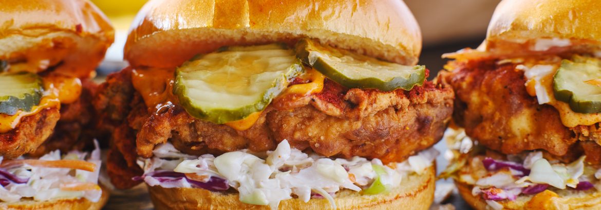 spicy nashville hot chicken sandwich with coleslaw and pickles in a row