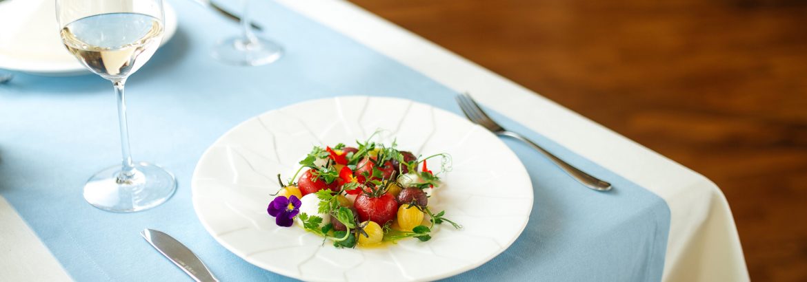 Gourmet peeled tomatoes salad on the table with a glass of white wine