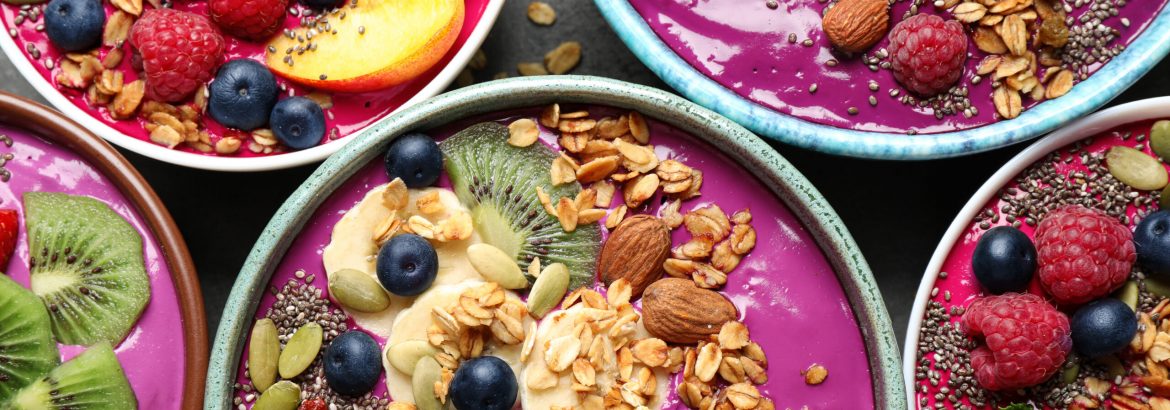 Delicious acai smoothie with toppings in bowls on table, flat lay