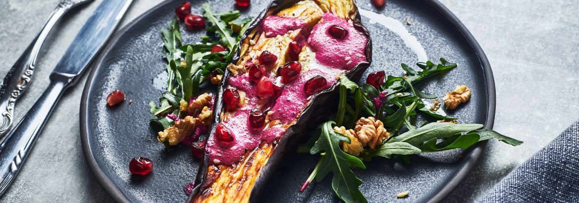 Roasted eggplant garnished with beetroot sauce, pomegranate seeds and walnuts.