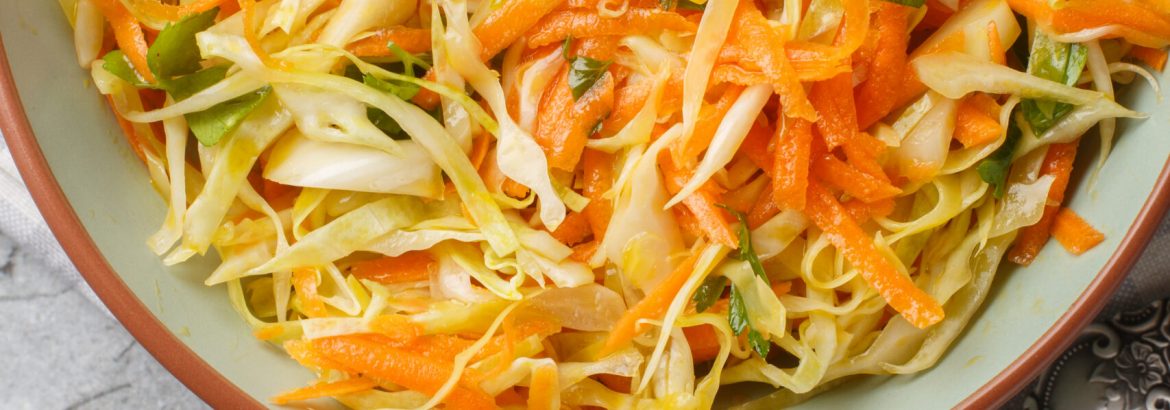 Lahanosalata Greek Cabbage Salad with carrot and parsley seasoned with olive oil closeup on the bowl on the table. Vertical top view from above