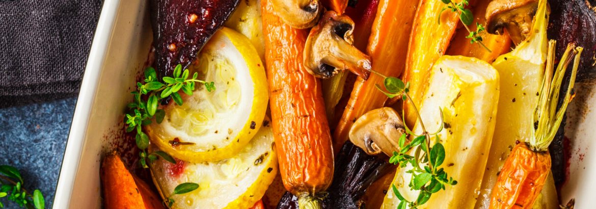 Baked carrots, sweet potatoes, beets and zucchini in oven dish, top view.