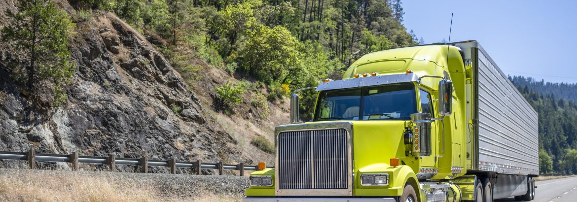 Bright lime stylish industrial grade long haul Big rig bonnet semi truck transporting frozen commercial cargo in refrigerator semi trailer running for delivery on the one way multiline highway road